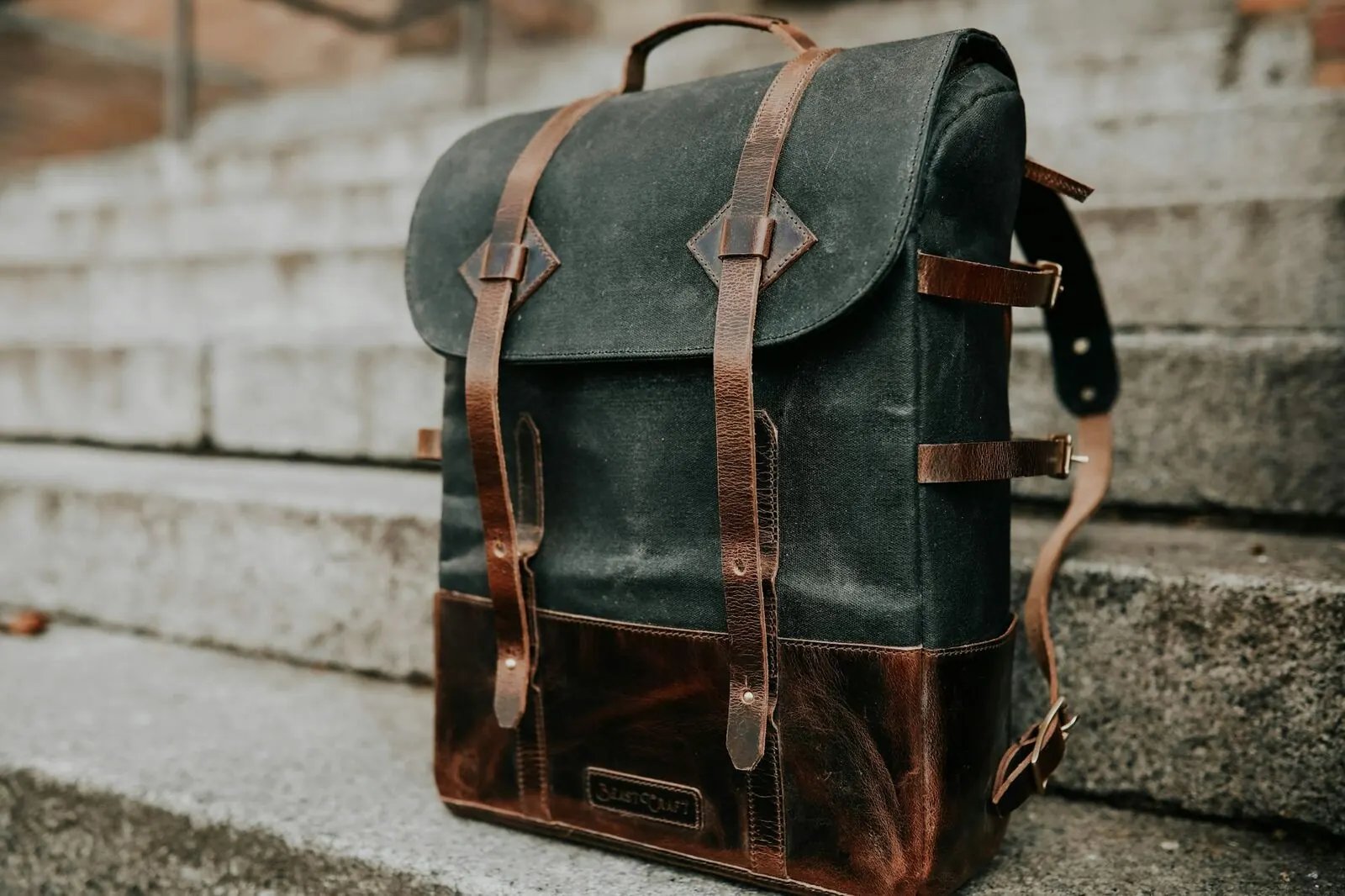 Brown leather backpack resting on concrete steps